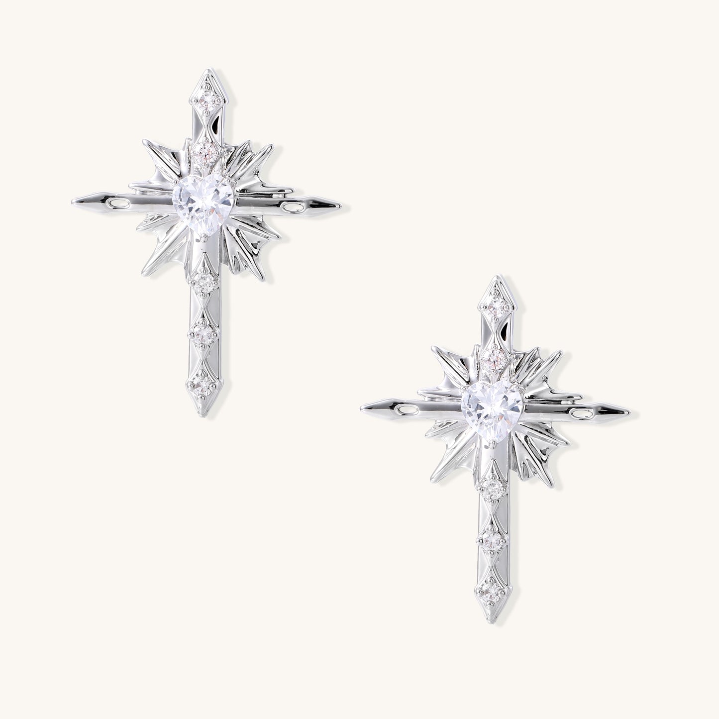 Gold-plated brass starburst cross earrings with central zirconia stones on white background.