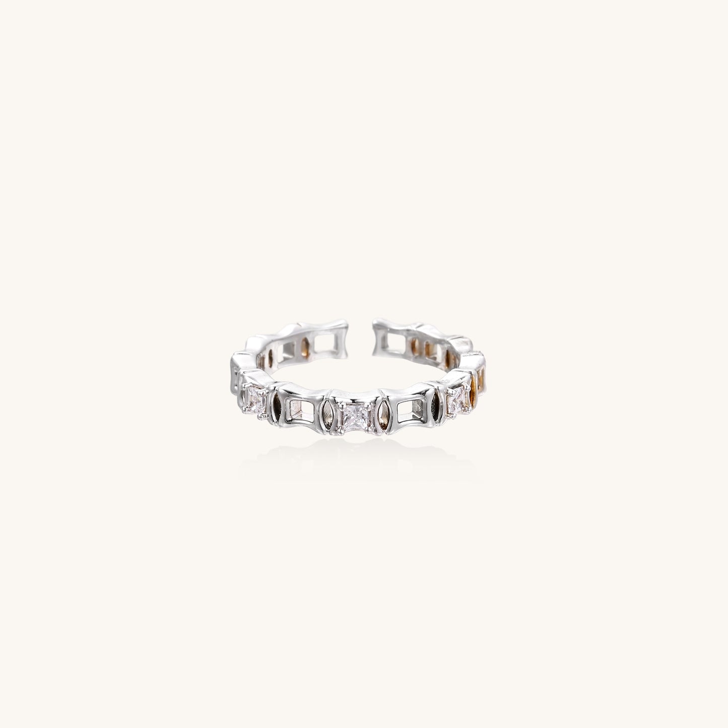 Close-up of geometric gold-plated ring with alternating rectangular blocks and zirconia crystals on white background.