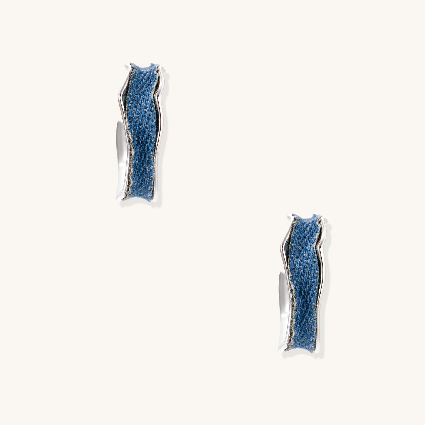 Small gold-plated hoop earrings with blue denim fabric insets on white background, showing casual-luxe styling.