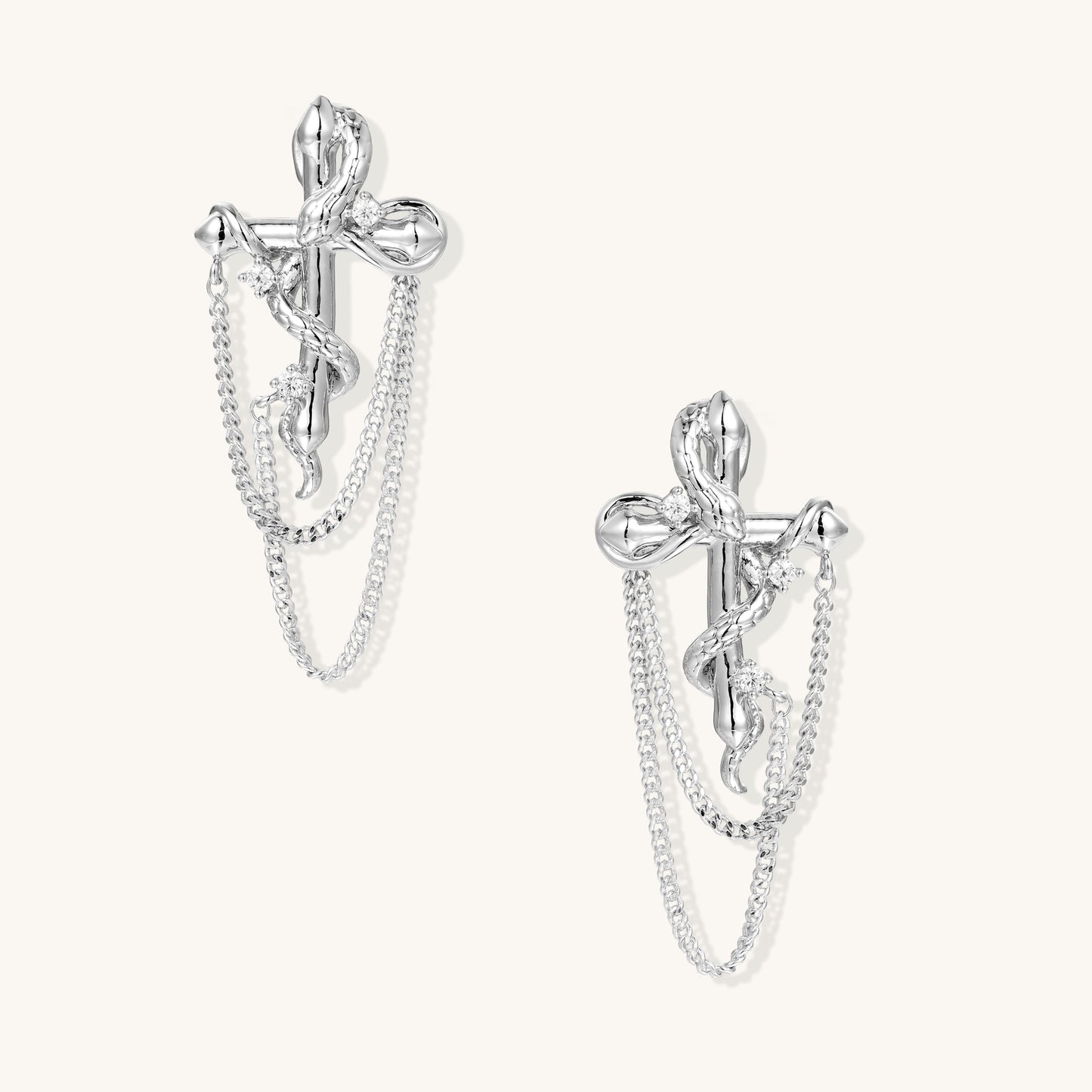 Silver-toned bow-shaped earrings with dangling chain details and zirconia accents on neutral background.