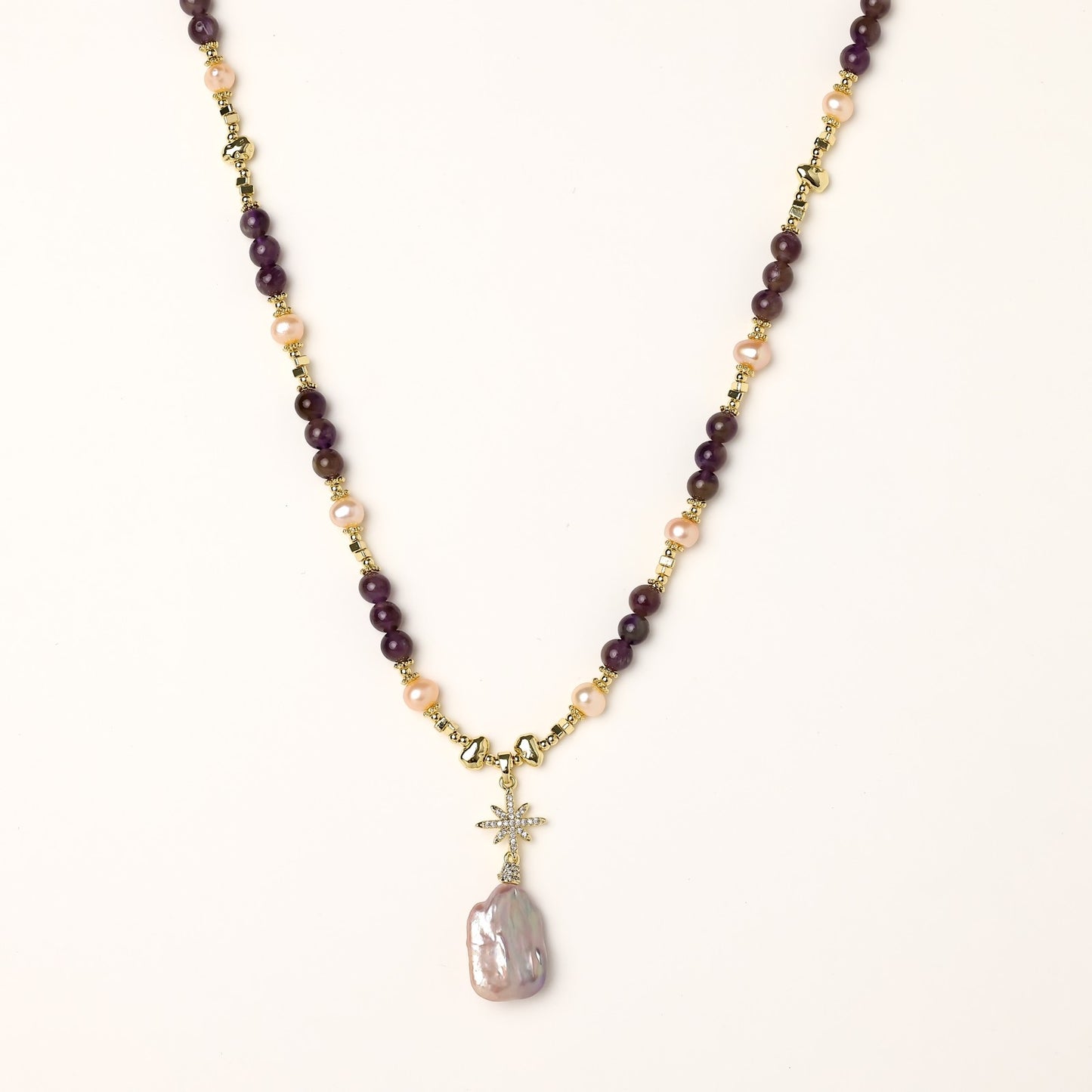 Gold-plated necklace with purple amethyst beads, pink pearls, and iridescent baroque pearl pendant beneath crystal star charm