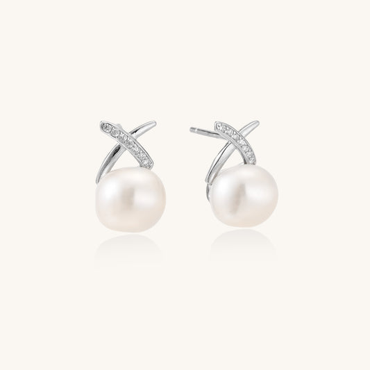 Sterling silver cross-shaped stud earrings with round freshwater pearls dangling below on white background.