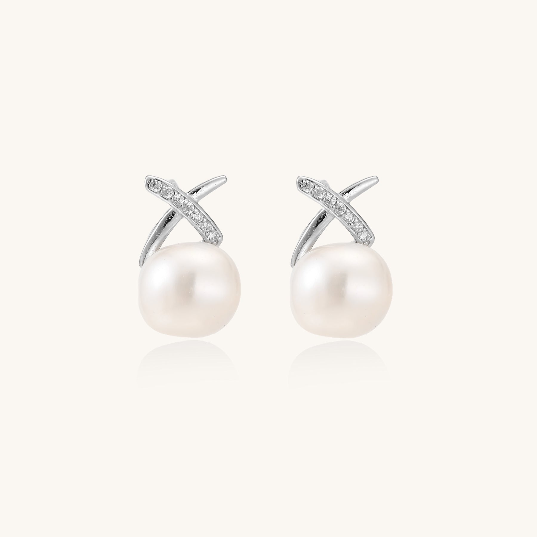 Sterling silver cross-shaped stud earrings with round freshwater pearls dangling below on white background.