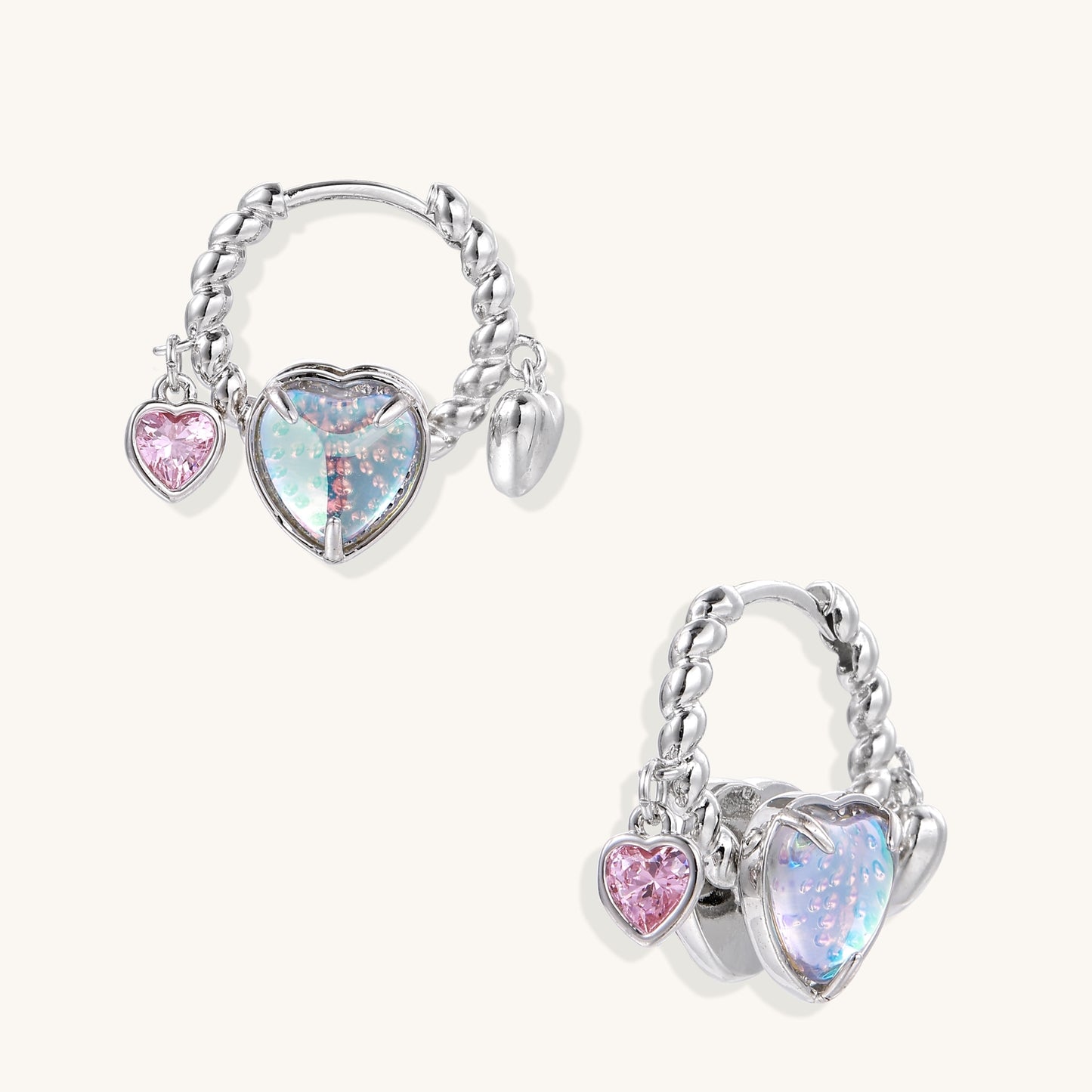 Gold-plated brass hoop earrings with three heart charms including iridescent turquoise and pink hearts on white background.