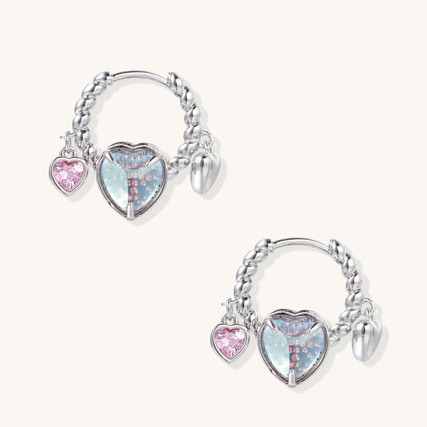 Gold-plated brass hoop earrings with three heart charms including iridescent turquoise and pink hearts on white background.