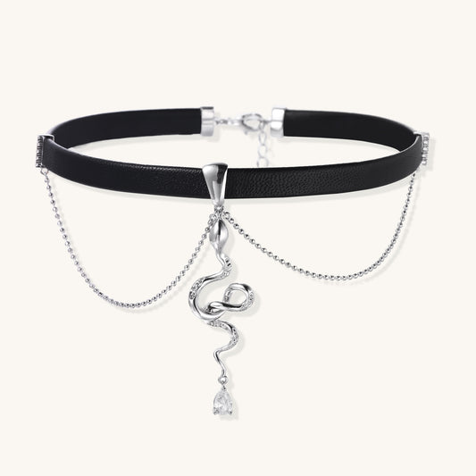 Black leather choker with gold-plated serpent pendant and crystal droplet on white background, adjustable chain design