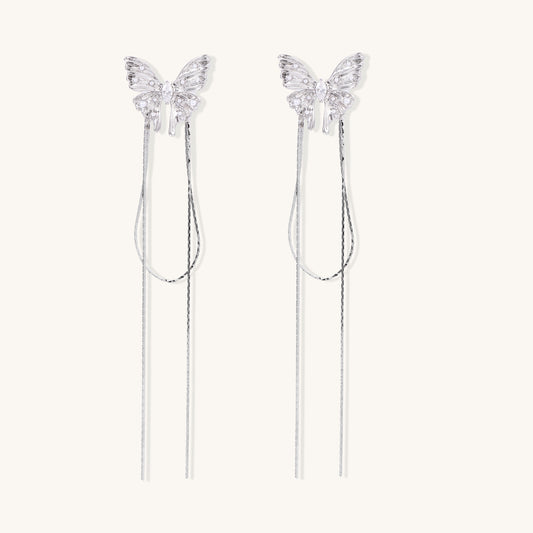 Delicate drop earrings with clear crystal butterfly tops and long metallic chain dangles on white background.