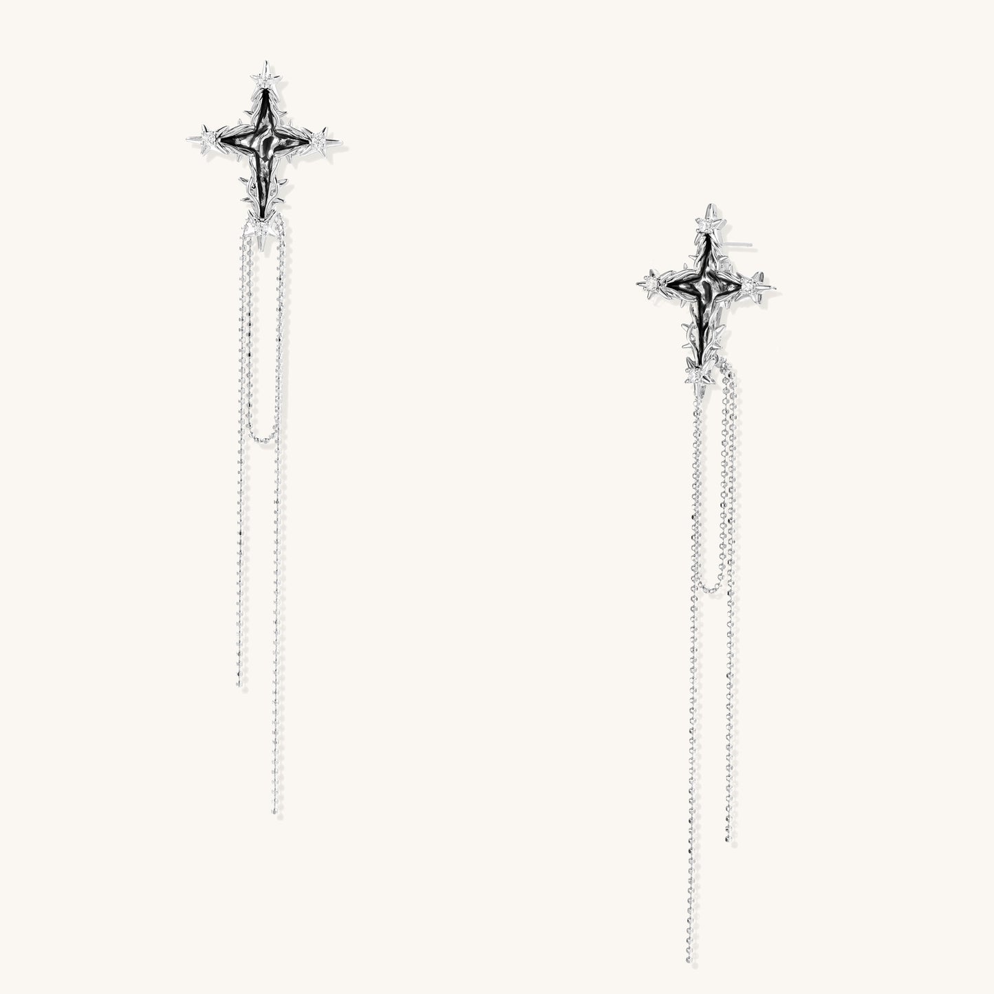 Long silver-toned cross earrings with star accents and delicate chain dangles on white background.