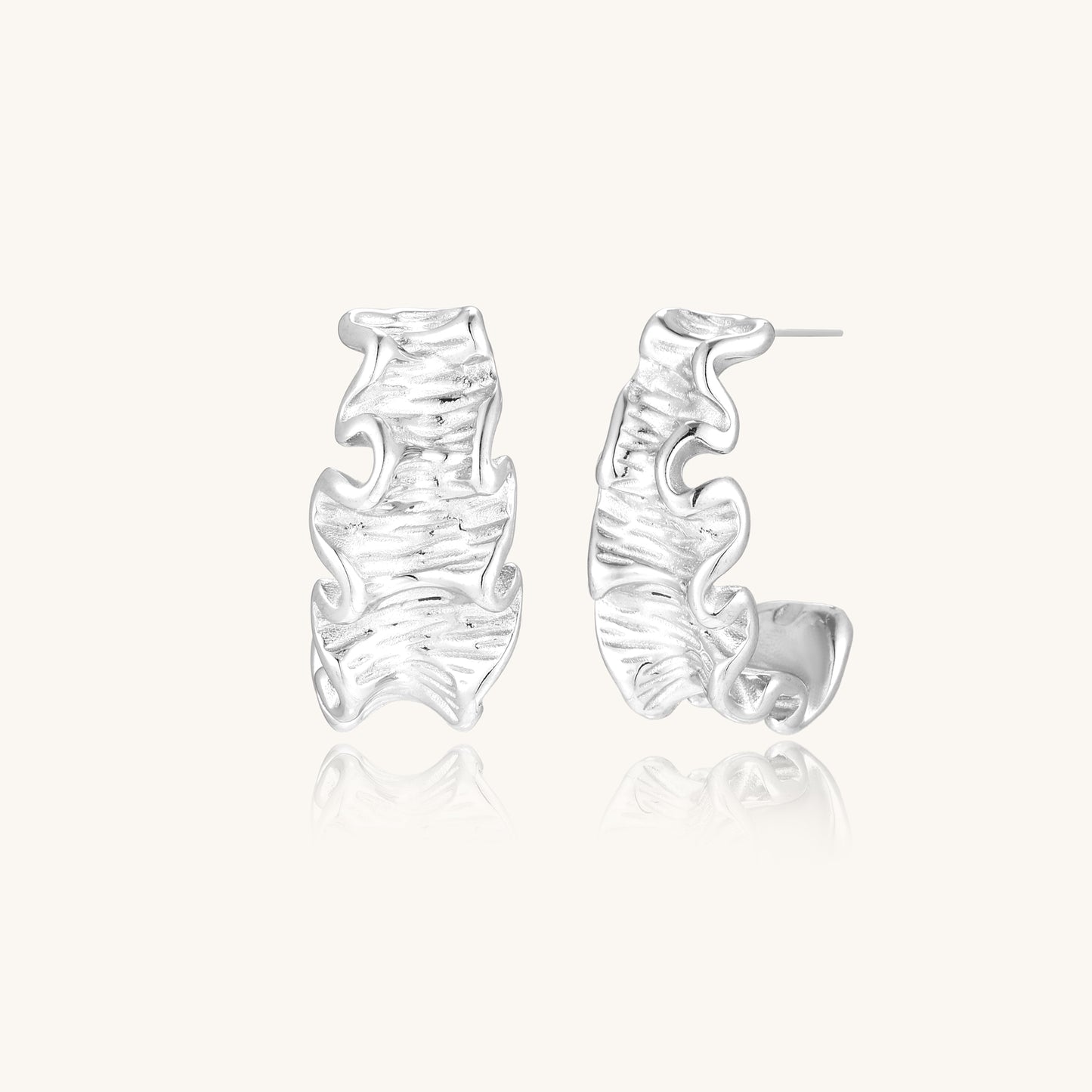 Textured gold-plated hoop earrings with flowing ripple design displayed on clean white background.