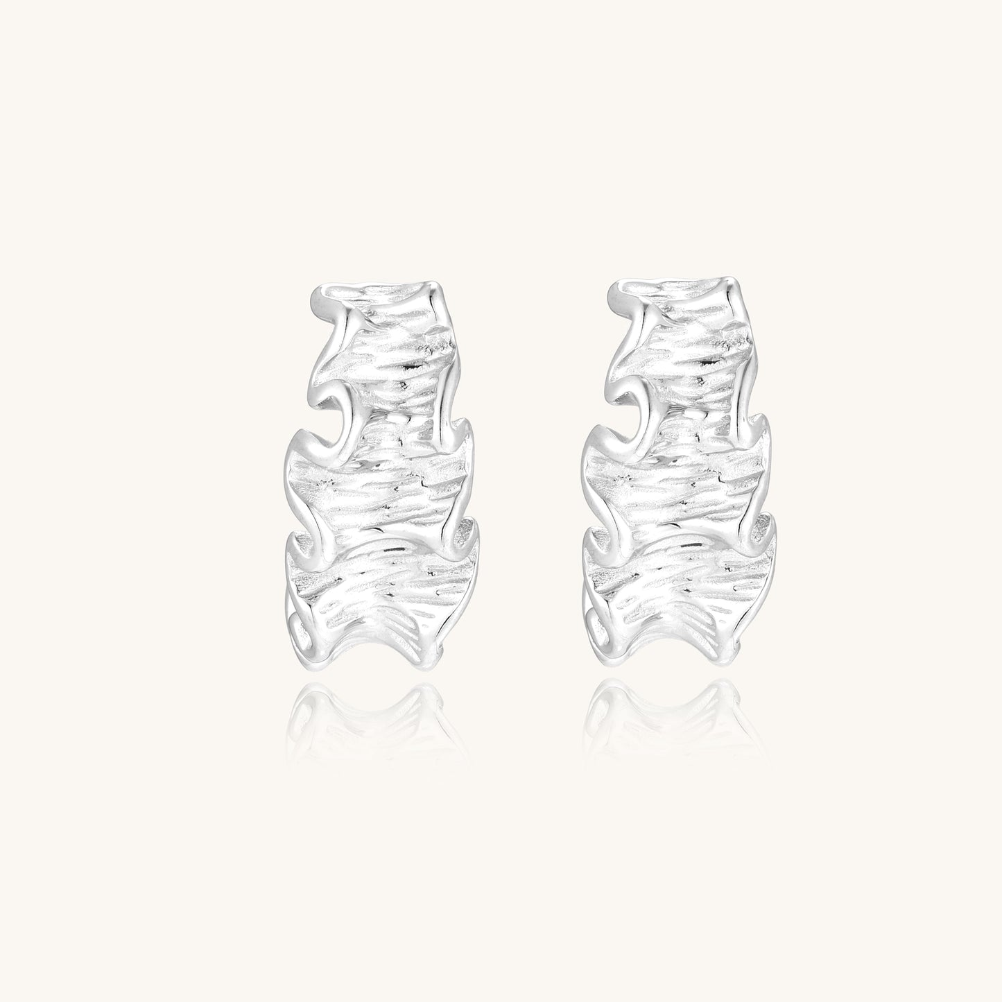 Textured gold-plated hoop earrings with flowing ripple design displayed on clean white background.