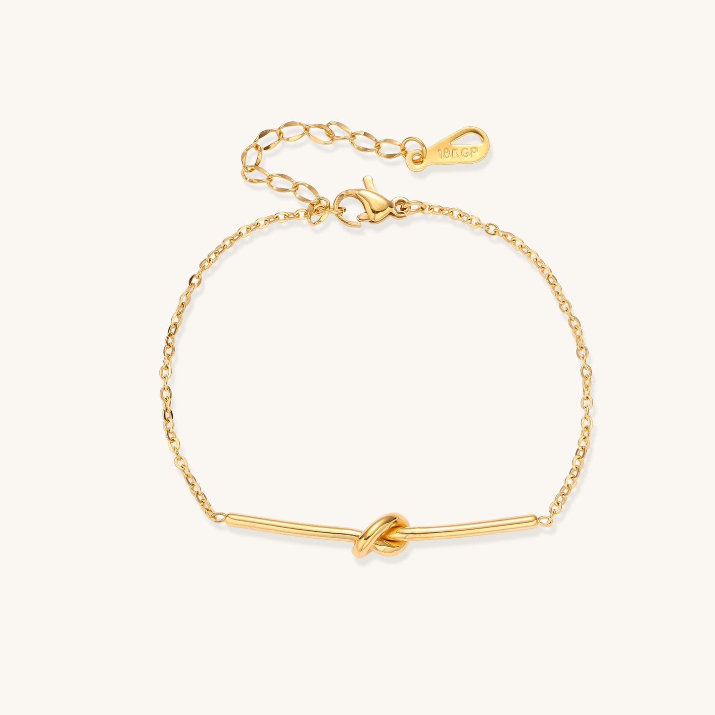 Delicate gold-plated chain bracelet with twisted knot bar detail and adjustable extender chain on white background.