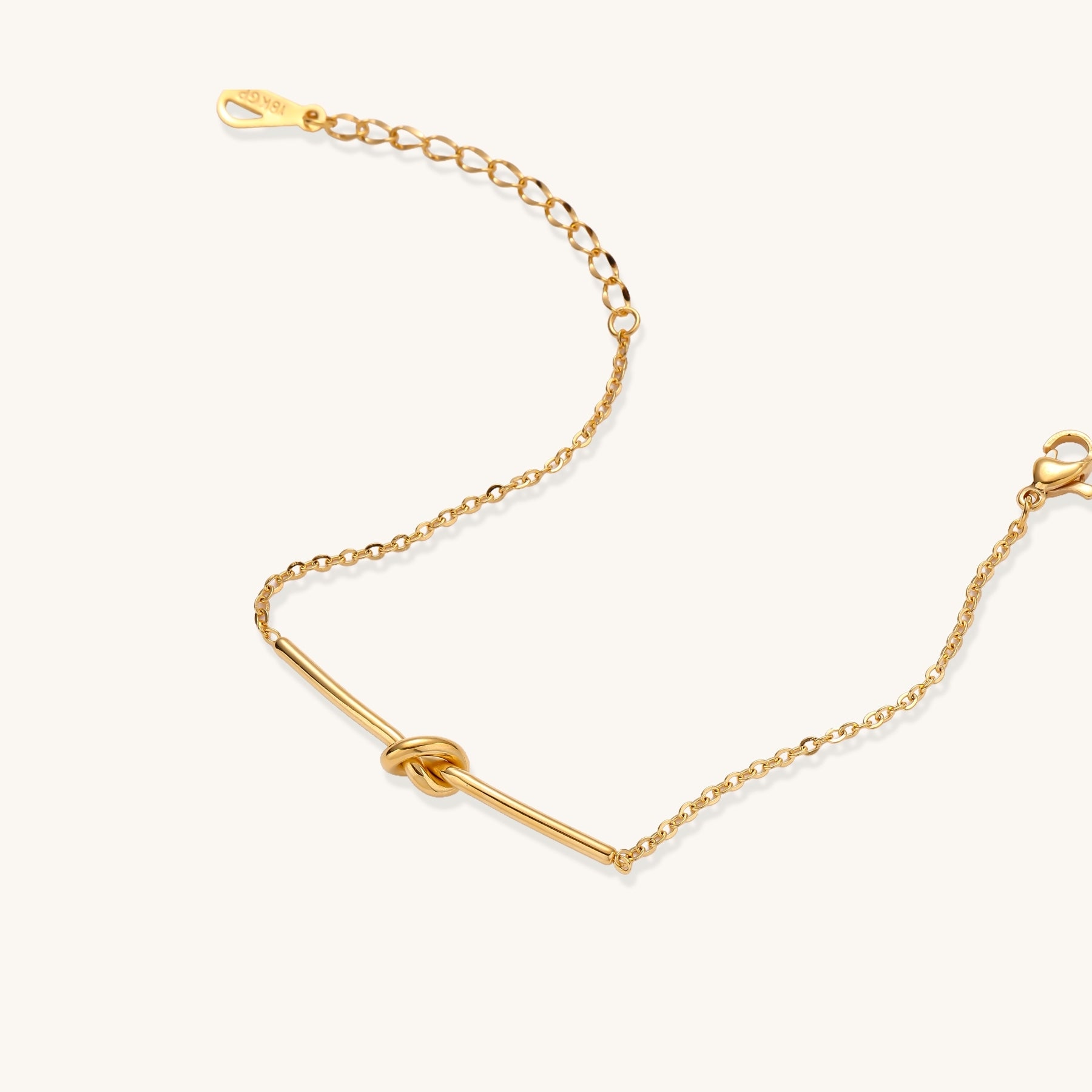 Delicate gold-plated chain bracelet with twisted knot bar detail and adjustable extender chain on white background.