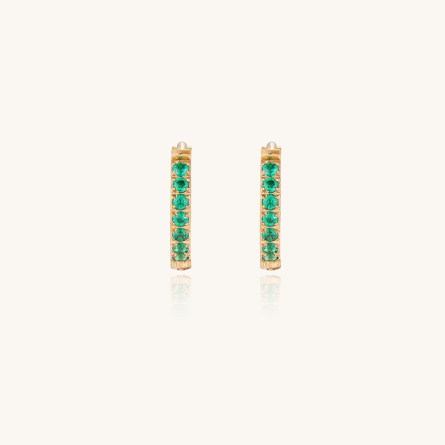 Small gold-plated huggie hoop earrings with emerald green cubic zirconia stones, one open showing hinge mechanism